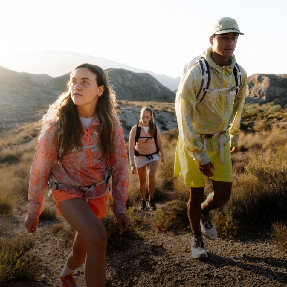 Drei Wanderer in sommerlicher Funktionskleidung wandern auf einem Berg