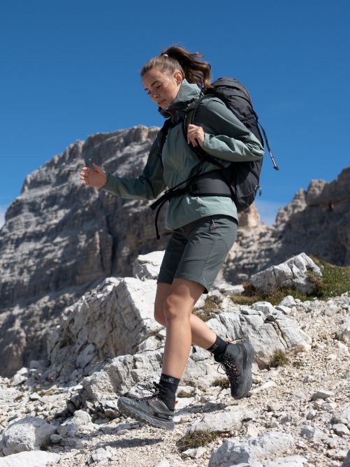 Wandererin mit großem Rucksack läuft bergabwärts