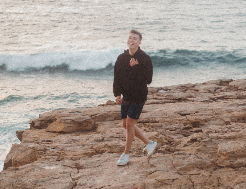 Andre sitting on a rock by the coast