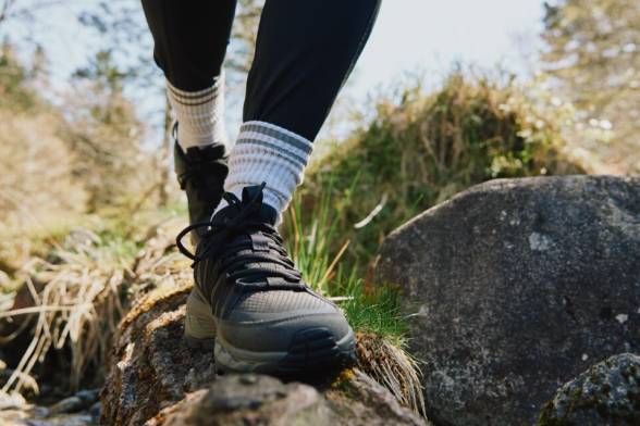Two hikers from behind with packs on their backs, walking across a wooden bridge