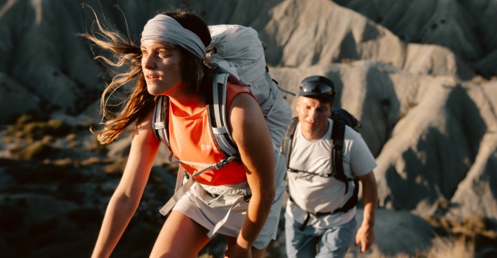 Frau und Mann in sommerlicher Wanderkleidung bei Sonnenuntergang