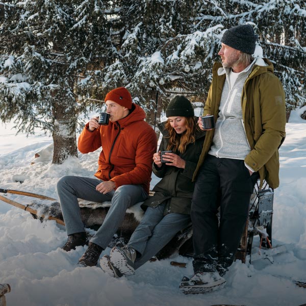 Drei Personen sitzen auf einem Schlitten im Schnee